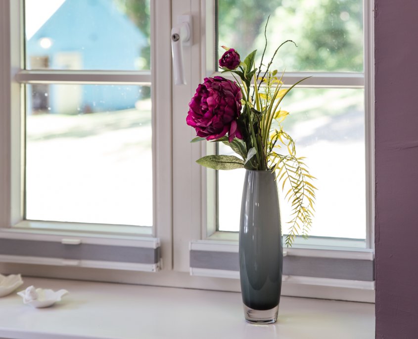 Vase mit Peonieen auf dem Fensterbrett